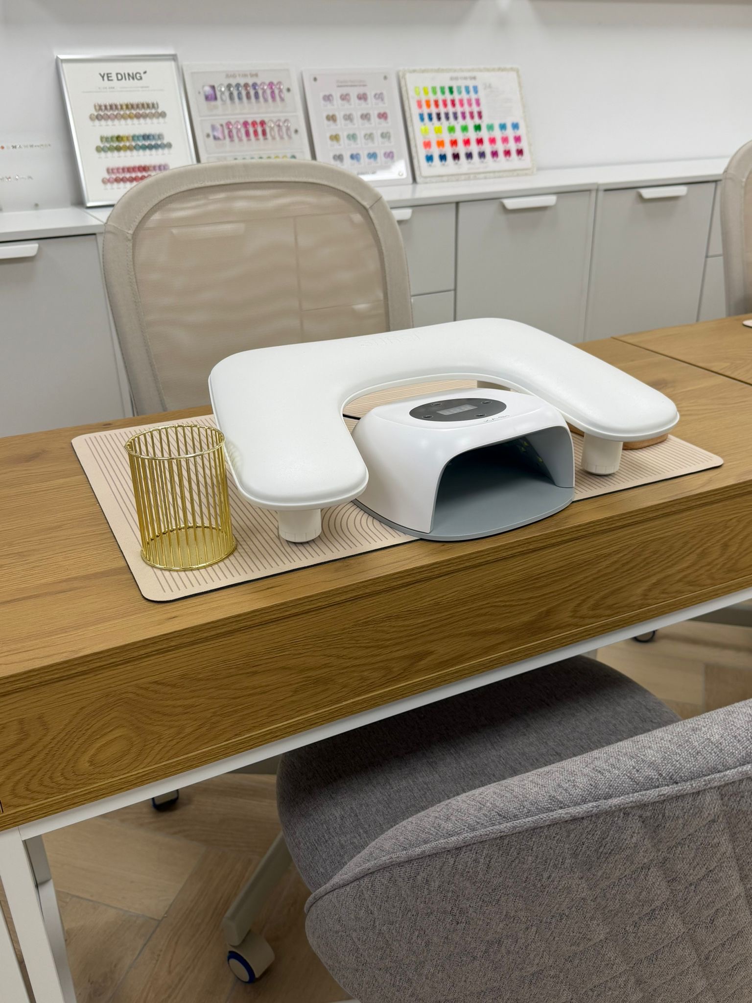 Een werkplek in de studio: witte UV-lamp op een houten tafel, kleurenkaarten aan de muur