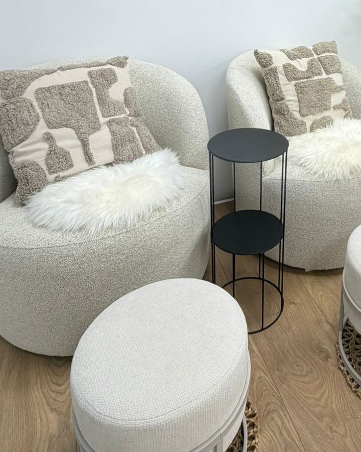 De zithoek in de studio: twee witte bouclé fauteuils met kussens en een zwart bijzettafeltje
