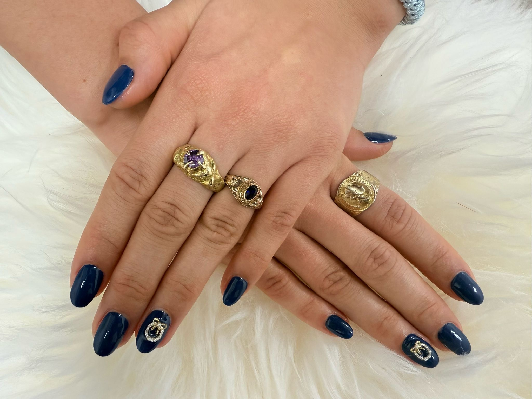 Navy amandelnagels met gouden ringen op wit bont