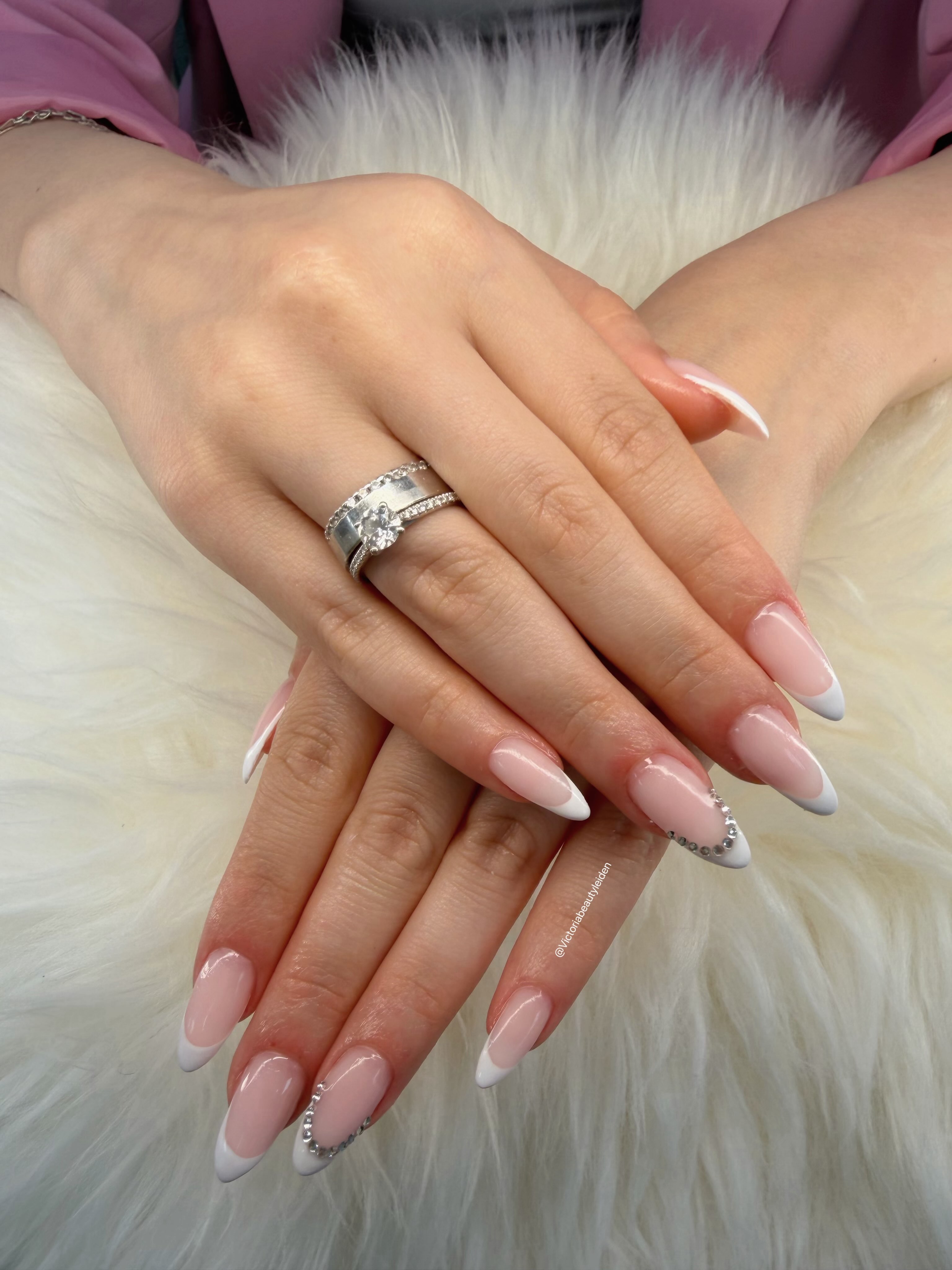 Witte French manicure met steentjes voor een bruid, op wit bont